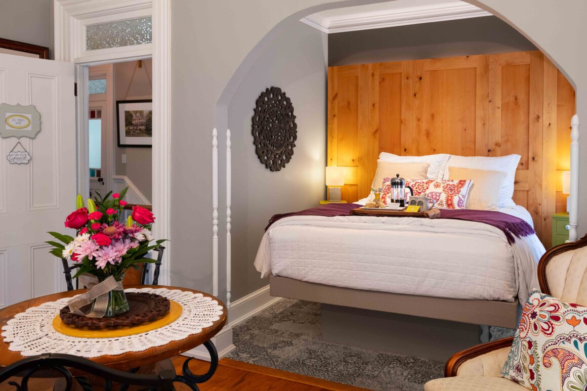 Cozy alcove bed in the Colonel Park Suite, styled with colorful pillows and a breakfast tray with French press coffee and pastries.