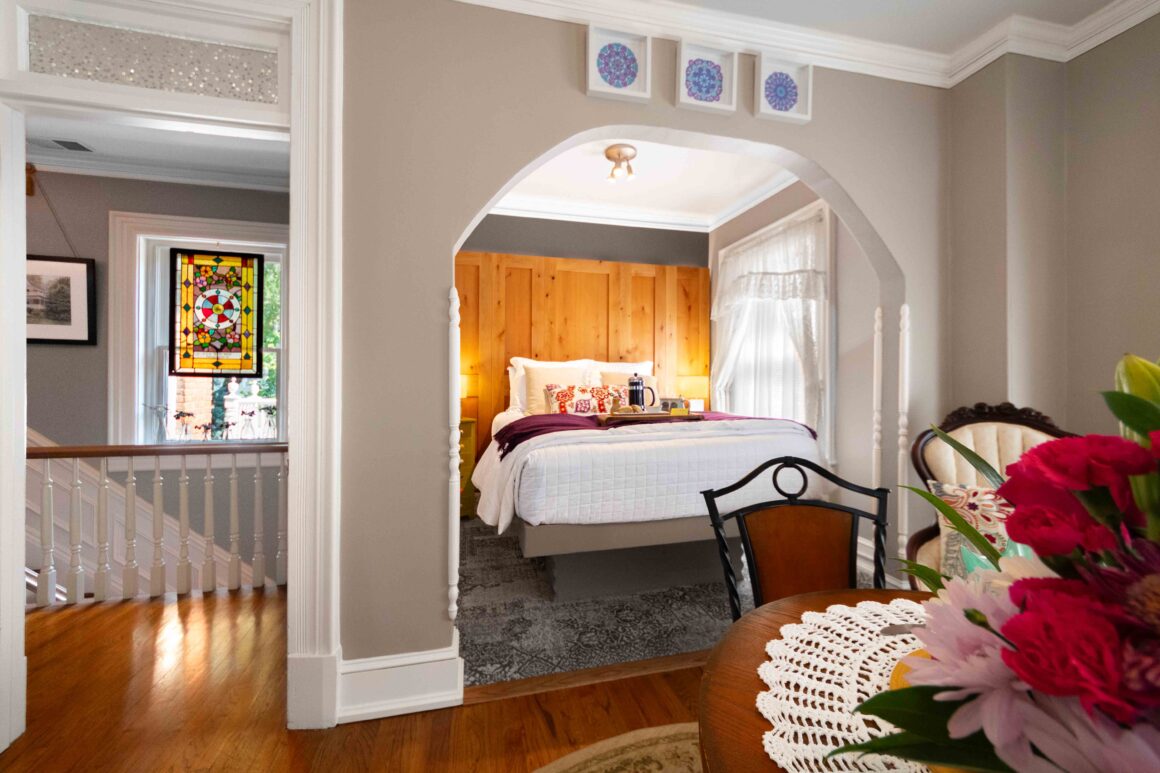Alternate angle of the bed alcove in the Colonel Park Suite, with a view toward the hallway and stained glass window.