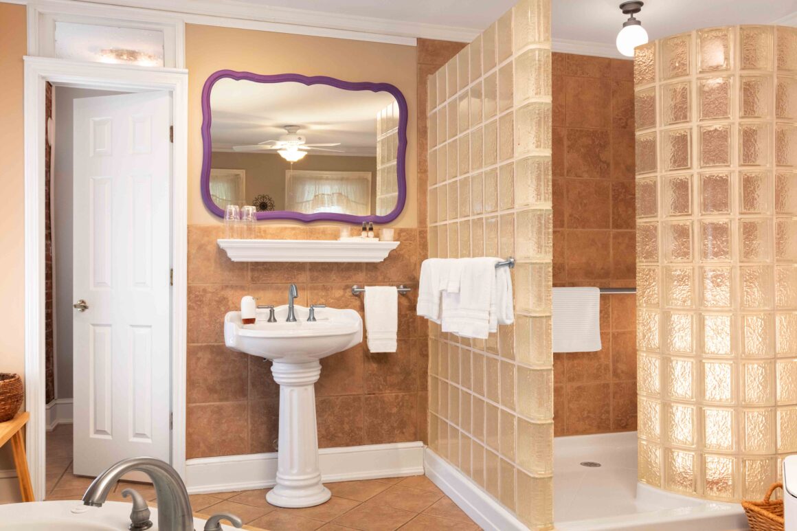 Close-up of the bathroom in the Colonel Park Suite showing the pedestal sink and glass-block shower.