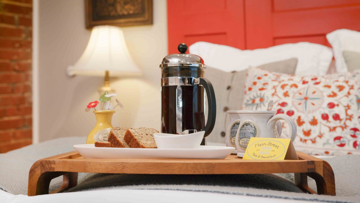 French press coffee and fresh-baked breakfast on a tray atop the bed.