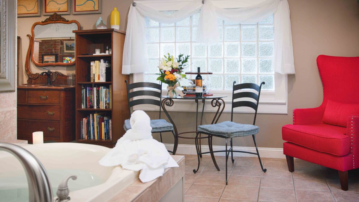 Whirlpool tub with seating area and red armchair in the Missouri River Suite.