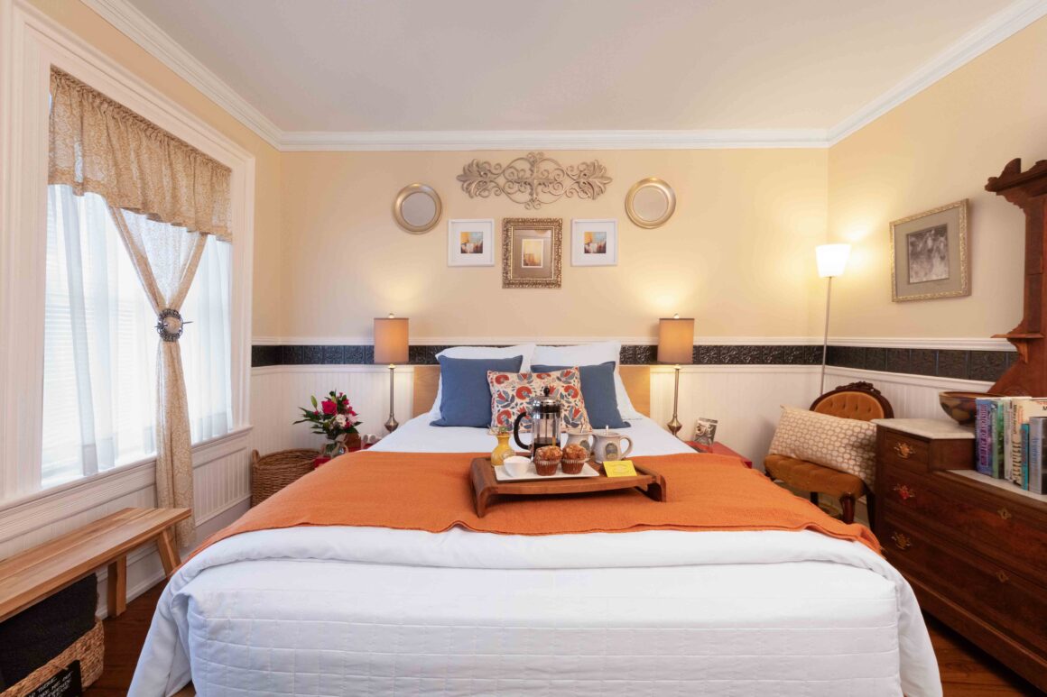 Front-facing view of the bed in Old Kate’s Room with a breakfast tray featuring French-press coffee and pastries.