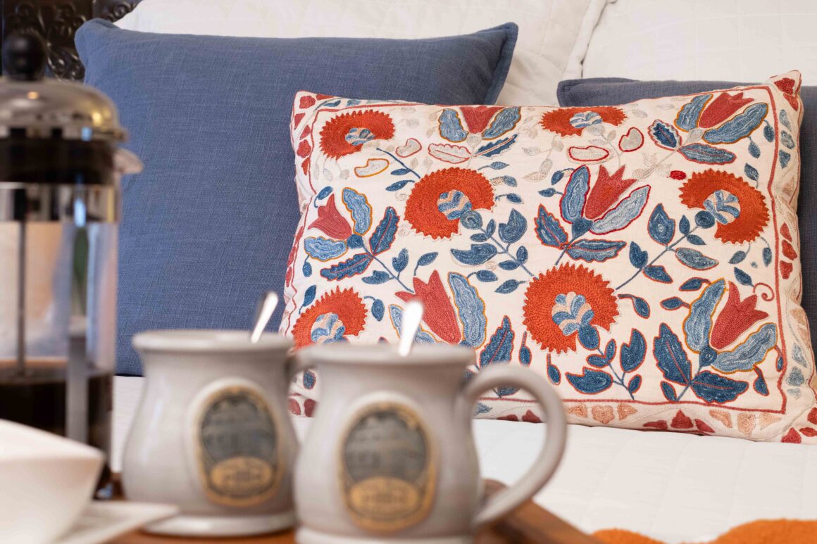 Detailed close-up of decorative pillows with textured embroidery on the bed in Old Kate’s Room.