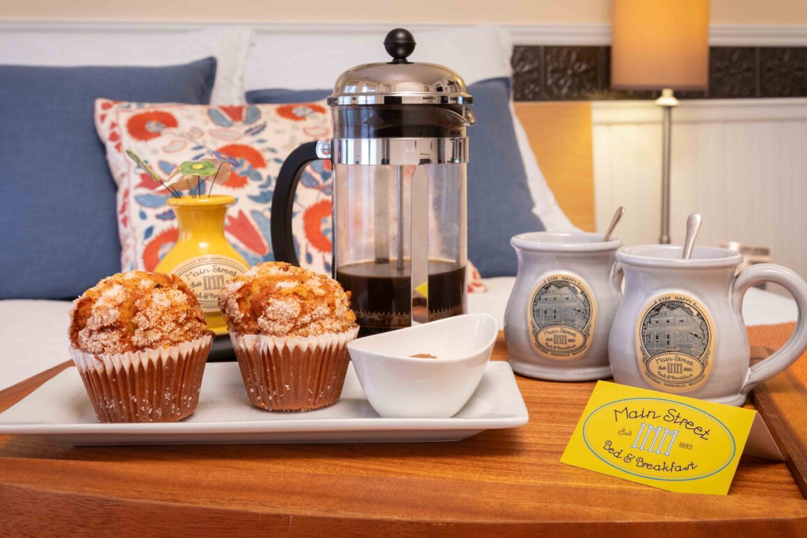 Close-up view of a breakfast tray with French-press coffee, mugs, and pastries in Old Kate’s Room.