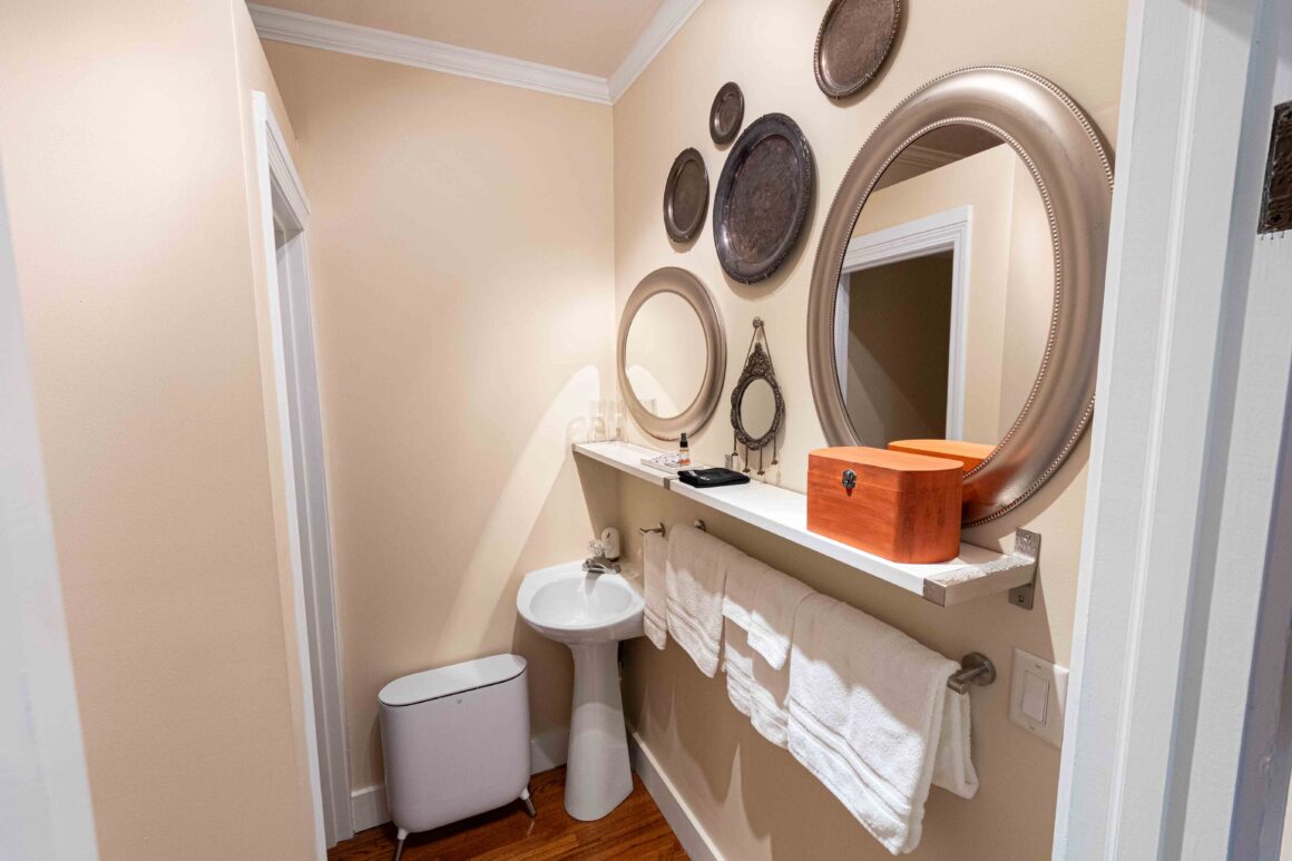 Sink and vanity area in Old Kate’s Room with mirrors and towel rack.