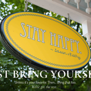 Stay Happy porch sign at the Main Street Inn with text overlay “Just Bring Yourself”
