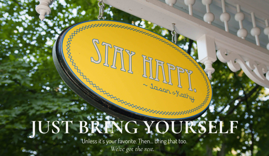 Stay Happy porch sign at the Main Street Inn with text overlay “Just Bring Yourself”