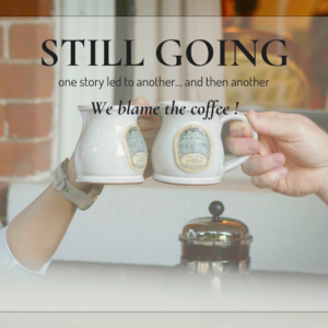 Two mugs raised in a toast at the Main Street Inn with overlay text reading “Still Going” reflecting on one year of stories and journaling.